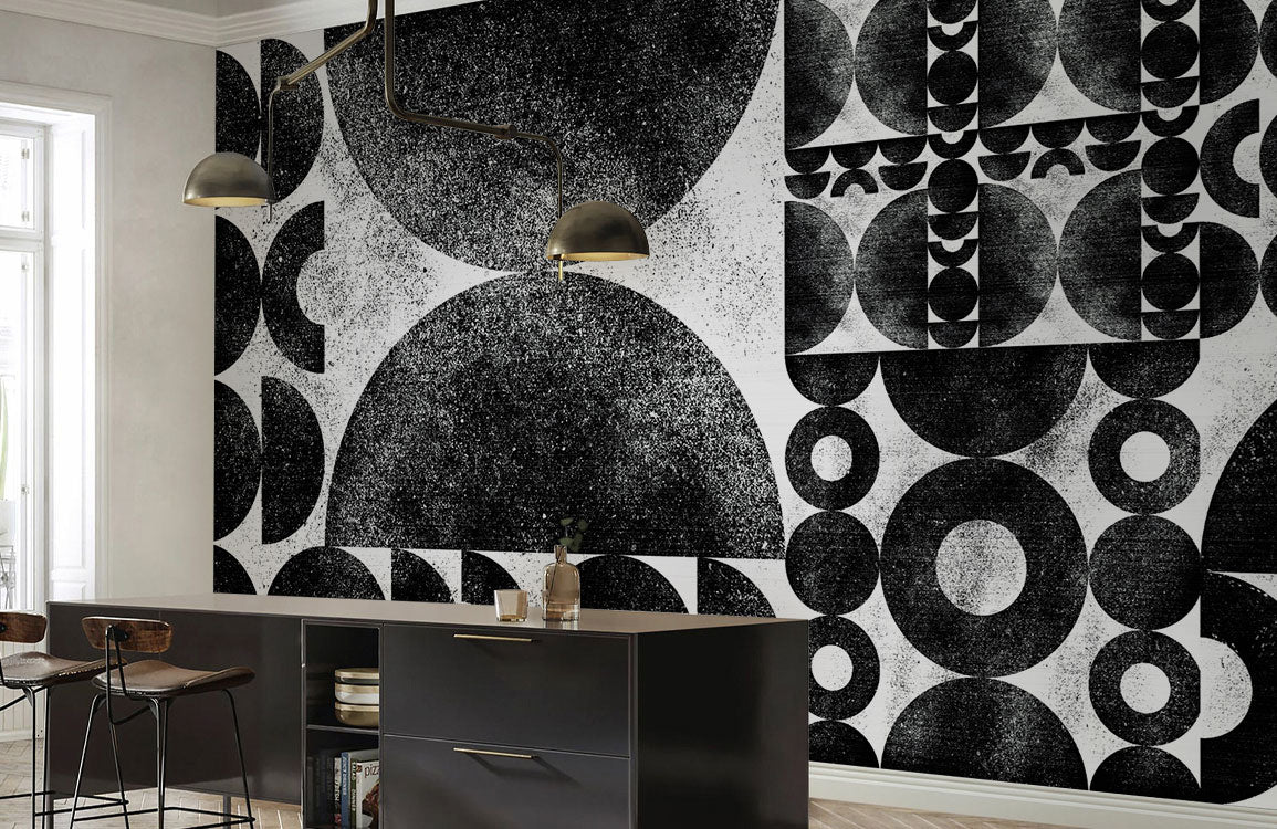 Monochrome geometric wallpaper in modern kitchen with black island, hanging lights, and wood flooring.