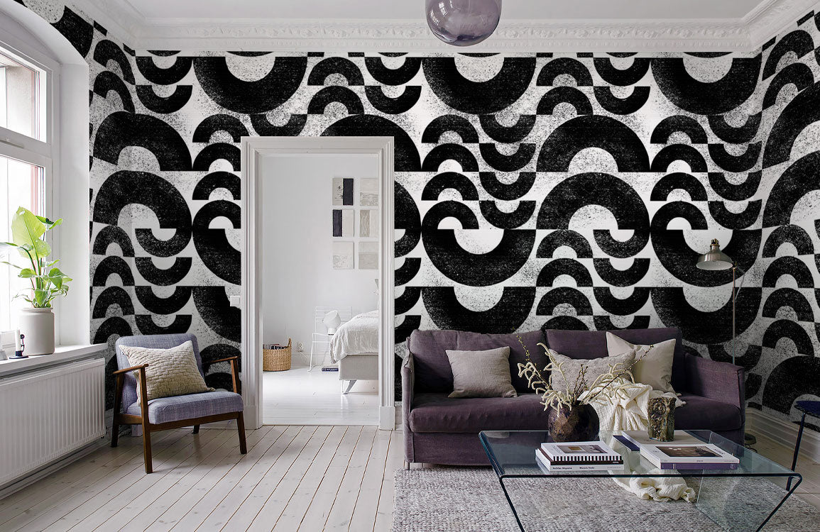 Monochrome geometric wave wallpaper in lounge with dark sofa, wooden flooring, and white walls.